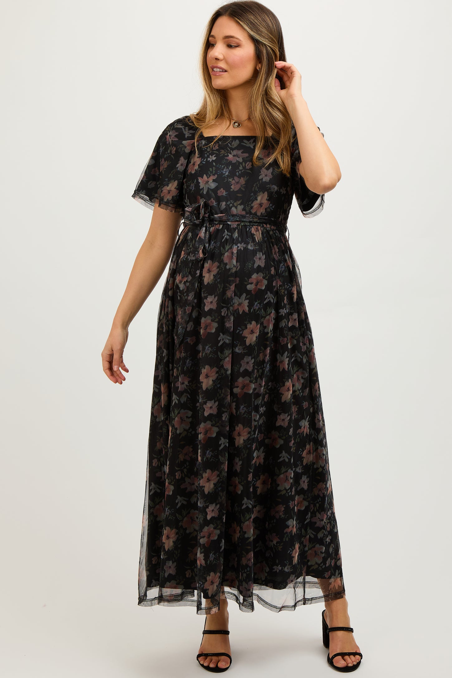 woman wearing a black floral print maternity maxi dress with short sleeves and a tie waist, highlighting her baby bump