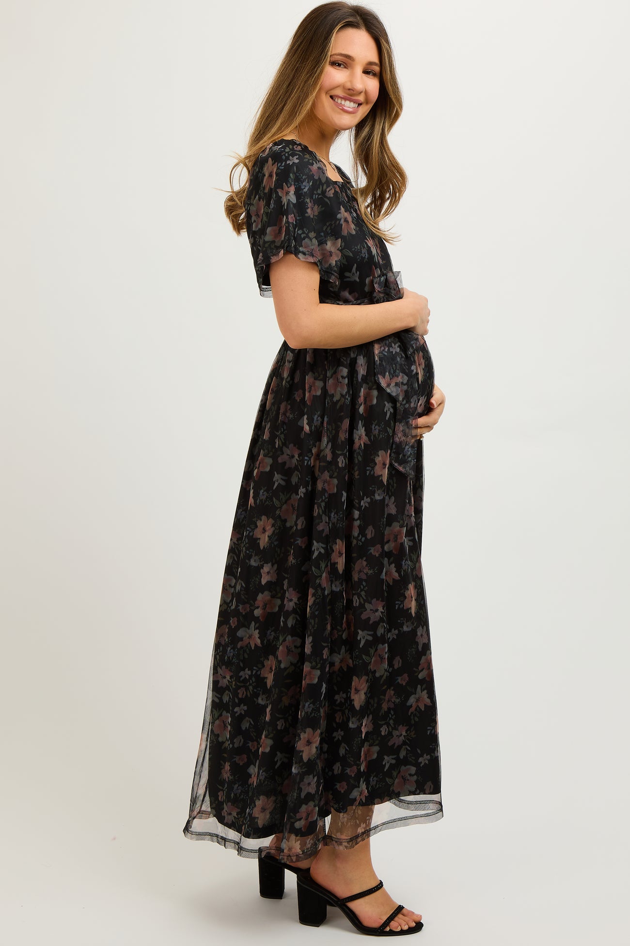 woman wearing a black floral maxi maternity dress and holding her baby bump