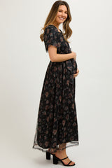 woman wearing a black floral maxi maternity dress and holding her baby bump