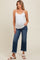 woman wearing a white maternity camisole top and blue wide-leg jeans, showing her baby bump