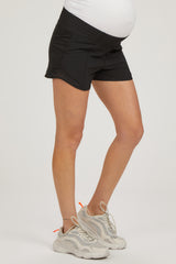 woman wearing black maternity shorts with a visible baby bump and white athletic shoes