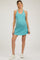woman wearing a teal maternity dress with a fitted silhouette and a baby bump visible, paired with white sneakers