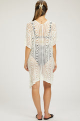 woman wearing a white crochet maternity cover-up with a loose fit and fringe details, showing a side view
