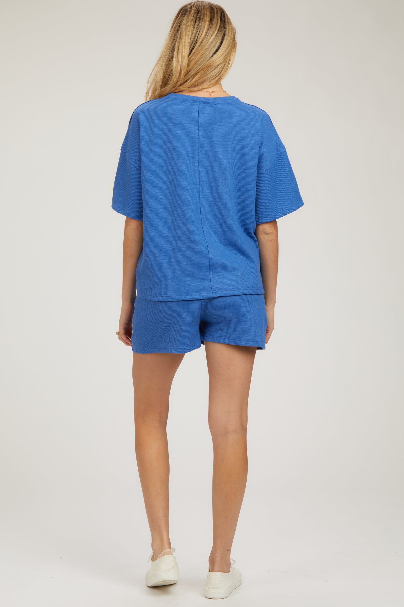 woman wearing a blue maternity short sleeve top and matching shorts, showing her back