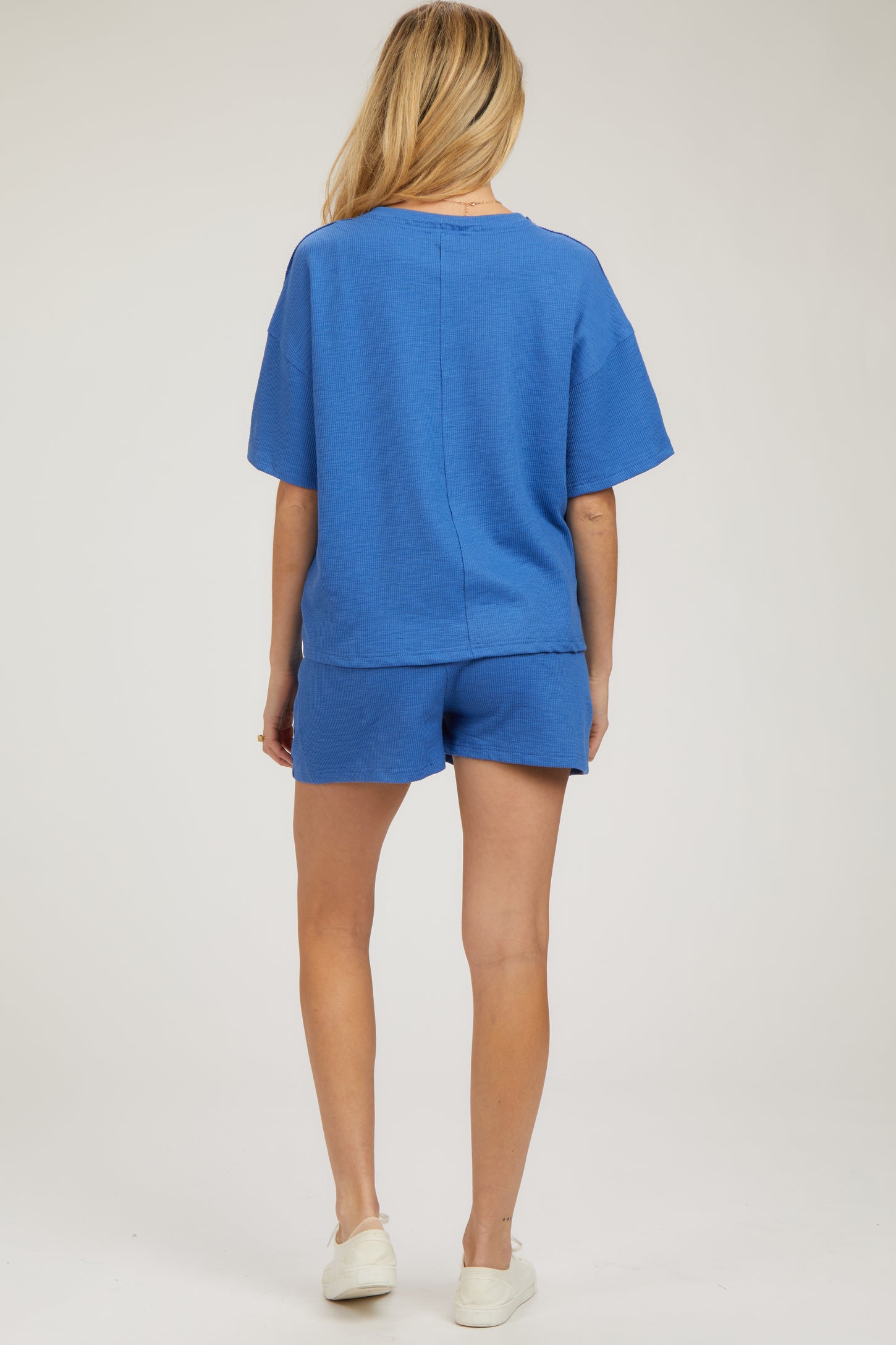 woman wearing a blue maternity short sleeve top and matching shorts, showing her back