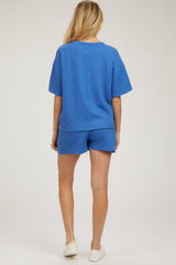 woman wearing a blue maternity short sleeve top and matching shorts, showing her back