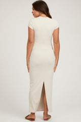 woman wearing a beige maternity maxi dress with short sleeves and a back slit
