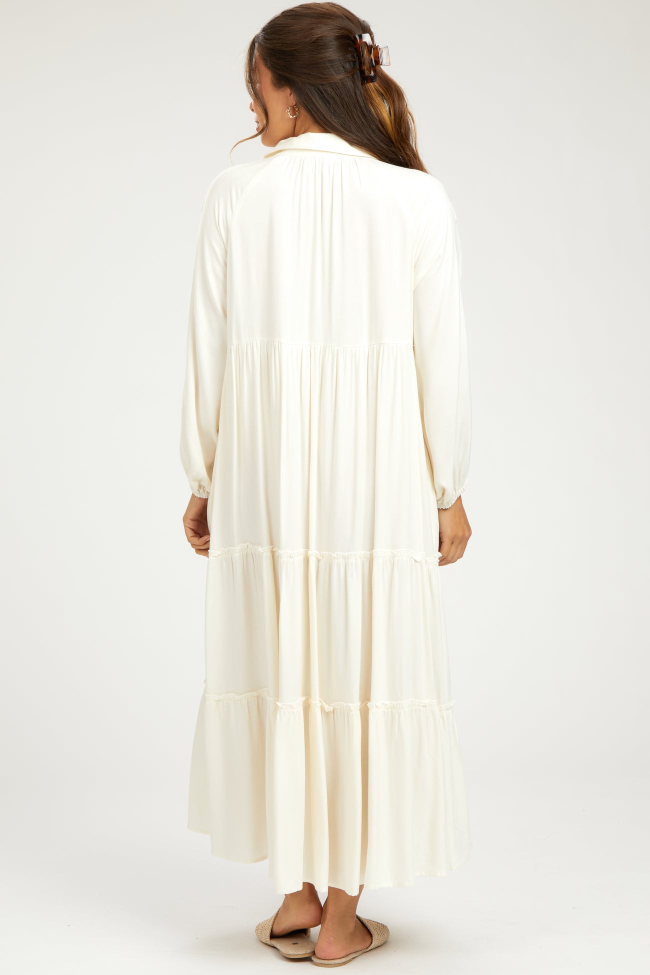 woman wearing a long white maternity dress with tiered ruffles, shown from the back