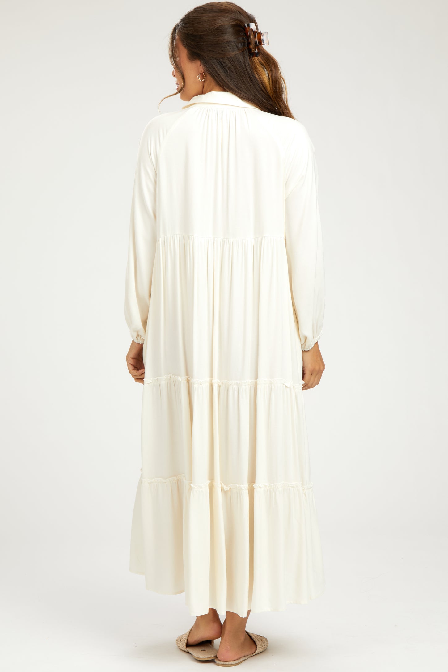 woman wearing a long white maternity dress with tiered ruffles, shown from the back