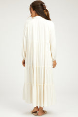 woman wearing a long white maternity dress with tiered ruffles, shown from the back