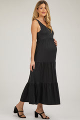 woman wearing a black tiered maternity dress, showcasing her baby bump while posing sideways