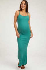 woman wearing a teal ribbed maternity maxi dress and gently cradling her baby bump