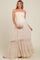 woman wearing a light beige maternity maxi dress with a smocked bodice and ruffled hem, holding her baby bump
