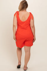 woman wearing a bright orange maternity plus romper with tied shoulder straps, showing the back view