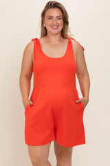 woman wearing a bright orange maternity plus romper with bow tie straps and pockets