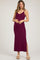 woman wearing a plum maternity maxi dress with a fitted silhouette and side slit, gently holding her baby bump