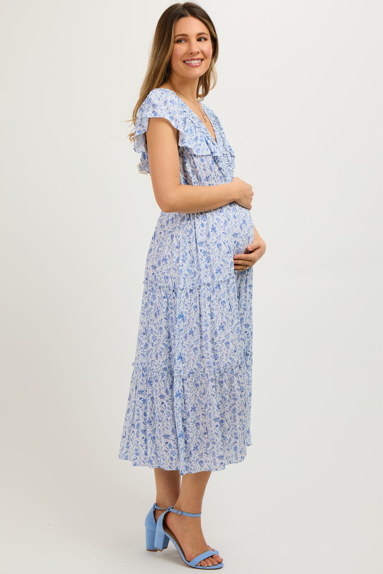 woman wearing a light blue floral maternity maxi dress and holding her baby bump