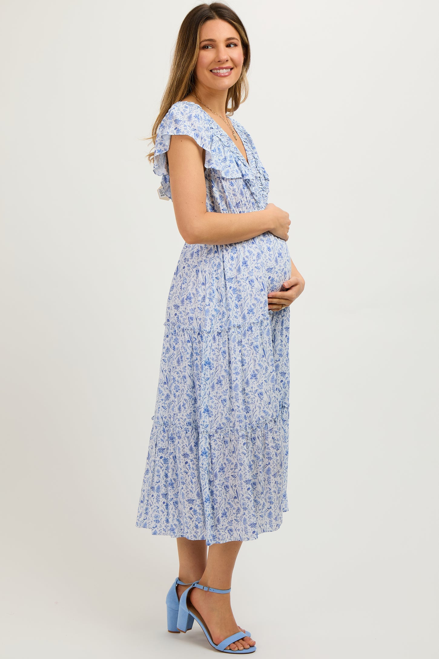 woman wearing a light blue floral maternity maxi dress and holding her baby bump