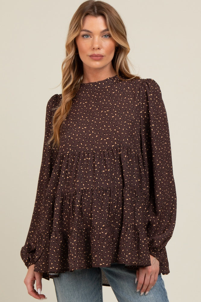 woman wearing a brown maternity top with a tiered ruffle design and a subtle spotted pattern