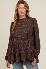 woman wearing a brown maternity top with a tiered ruffle design and a subtle spotted pattern