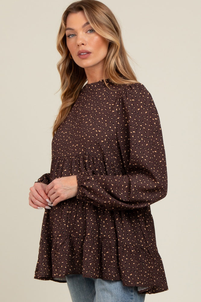 woman wearing a brown maternity top with a tiered design and subtle pattern, showcasing her baby bump