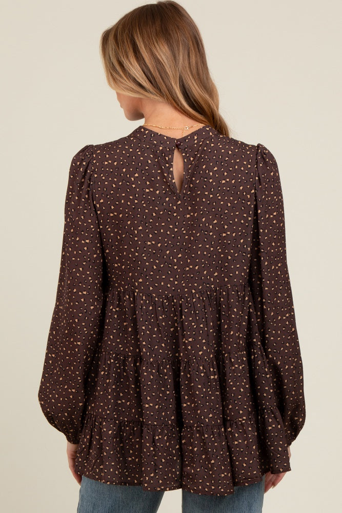 woman wearing a brown patterned maternity top with puffed sleeves and a tiered hem, showing the back view