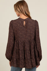 woman wearing a brown patterned maternity top with puffed sleeves and a tiered hem, showing the back view