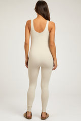 woman wearing a beige ribbed maternity jumpsuit with a scoop back and form-fitting design