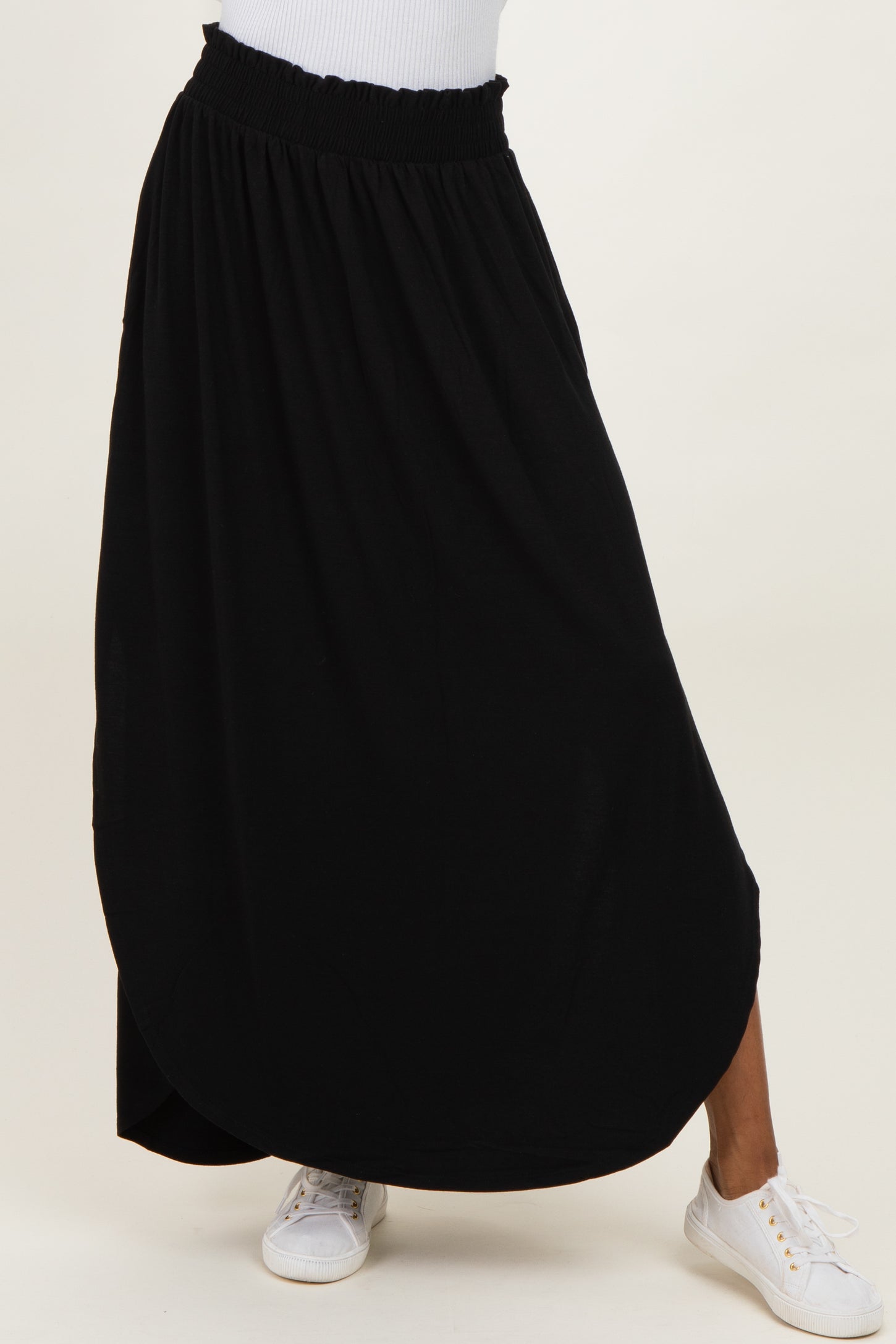 woman wearing a black maxi skirt with a smocked waistband and white sneakers