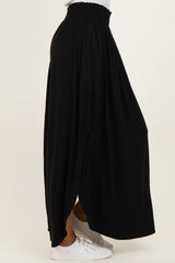woman wearing a black maxi skirt with a smocked waist and side slits, paired with white casual shoes