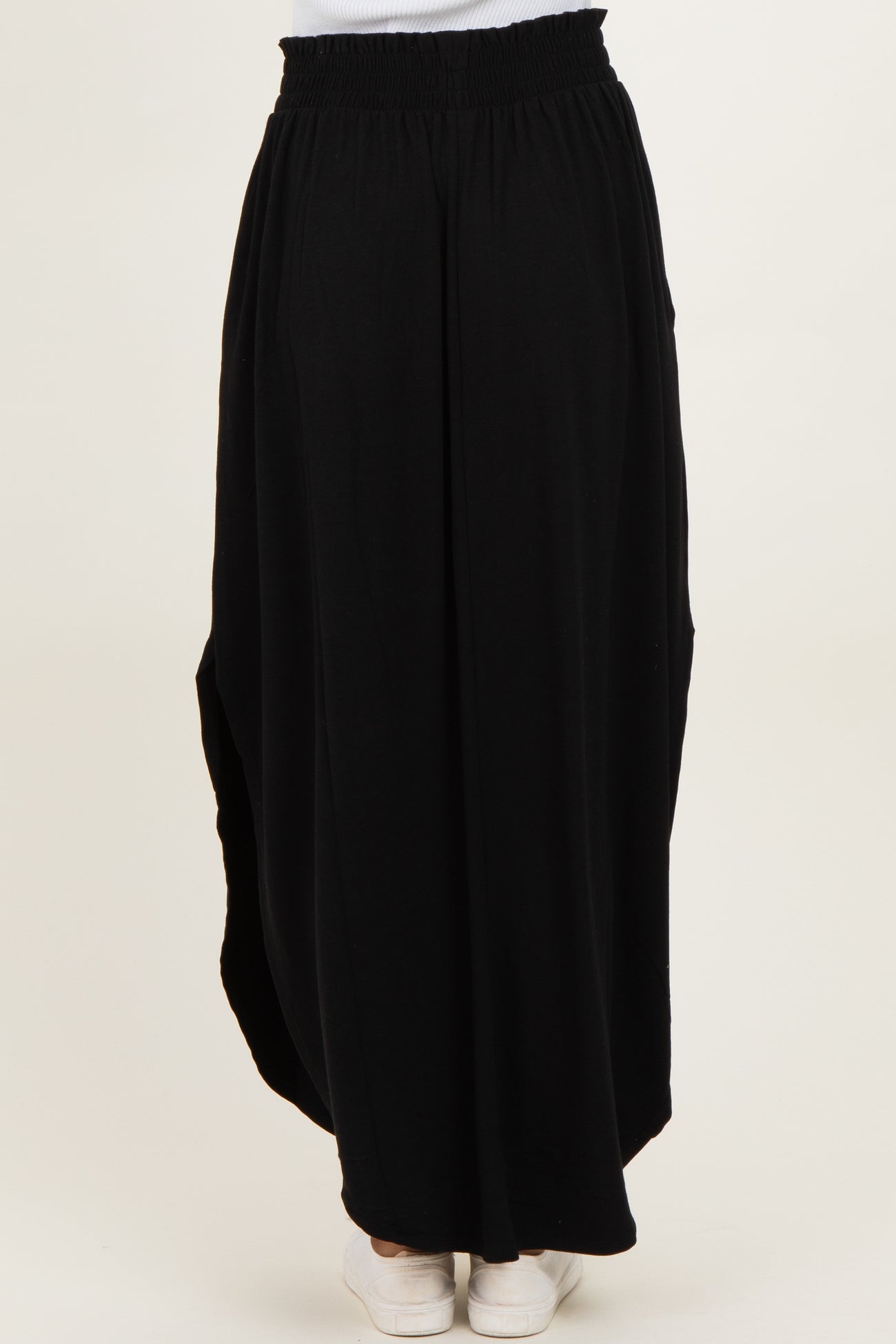 woman wearing a black maxi skirt with an elastic waistband and side pockets, shown from the back