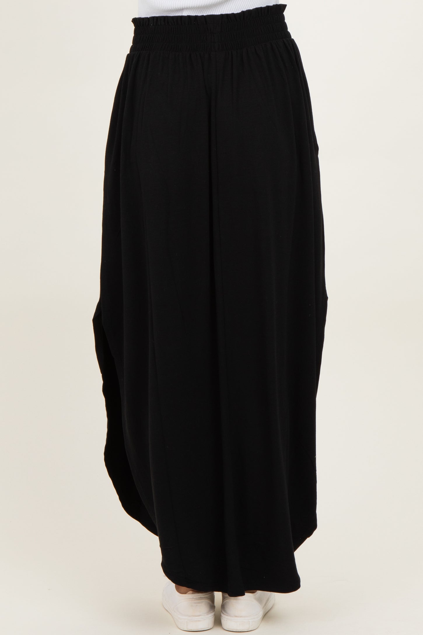 woman wearing a black maxi skirt with an elastic waistband and side pockets, shown from the back