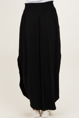 woman wearing a black maxi skirt with an elastic waistband and side pockets, shown from the back