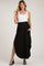 woman wearing a black maternity maxi skirt with pockets and a side slit, paired with a white tank top