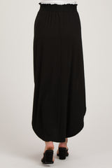 maternity wear black maxi skirt with smocked waistband, shown from the back, model wearing sandals