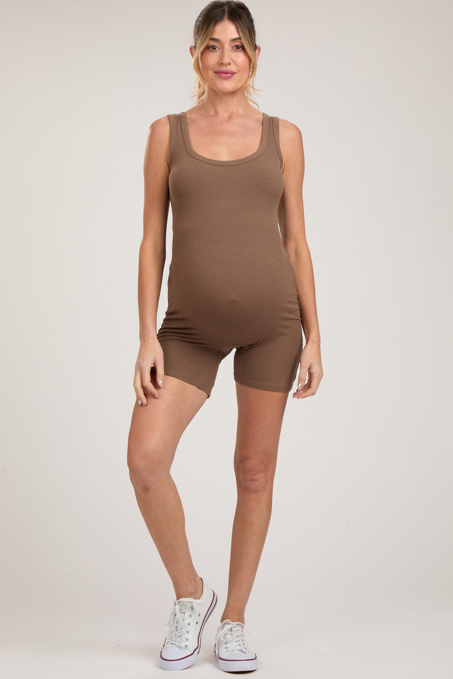 woman wearing a brown ribbed maternity bodysuit with shorts and showing her baby bump