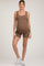 woman wearing a brown ribbed maternity bodysuit with shorts and showing her baby bump