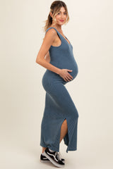 woman wearing a ribbed blue maternity maxi dress with a side slit and holding her baby bump
