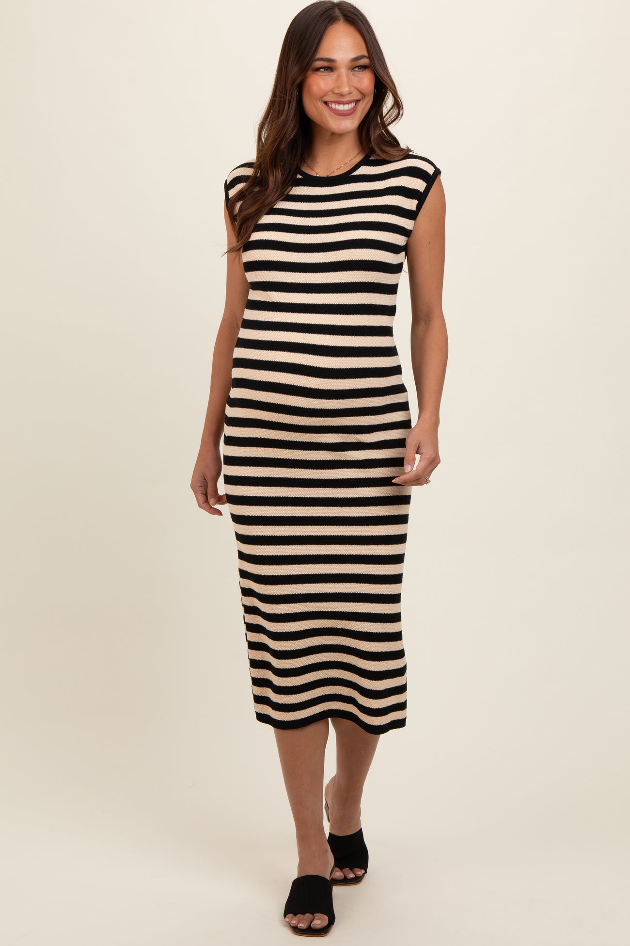 woman wearing a black and beige striped midi maternity dress with cap sleeves and a fitted silhouette, showing a baby bump