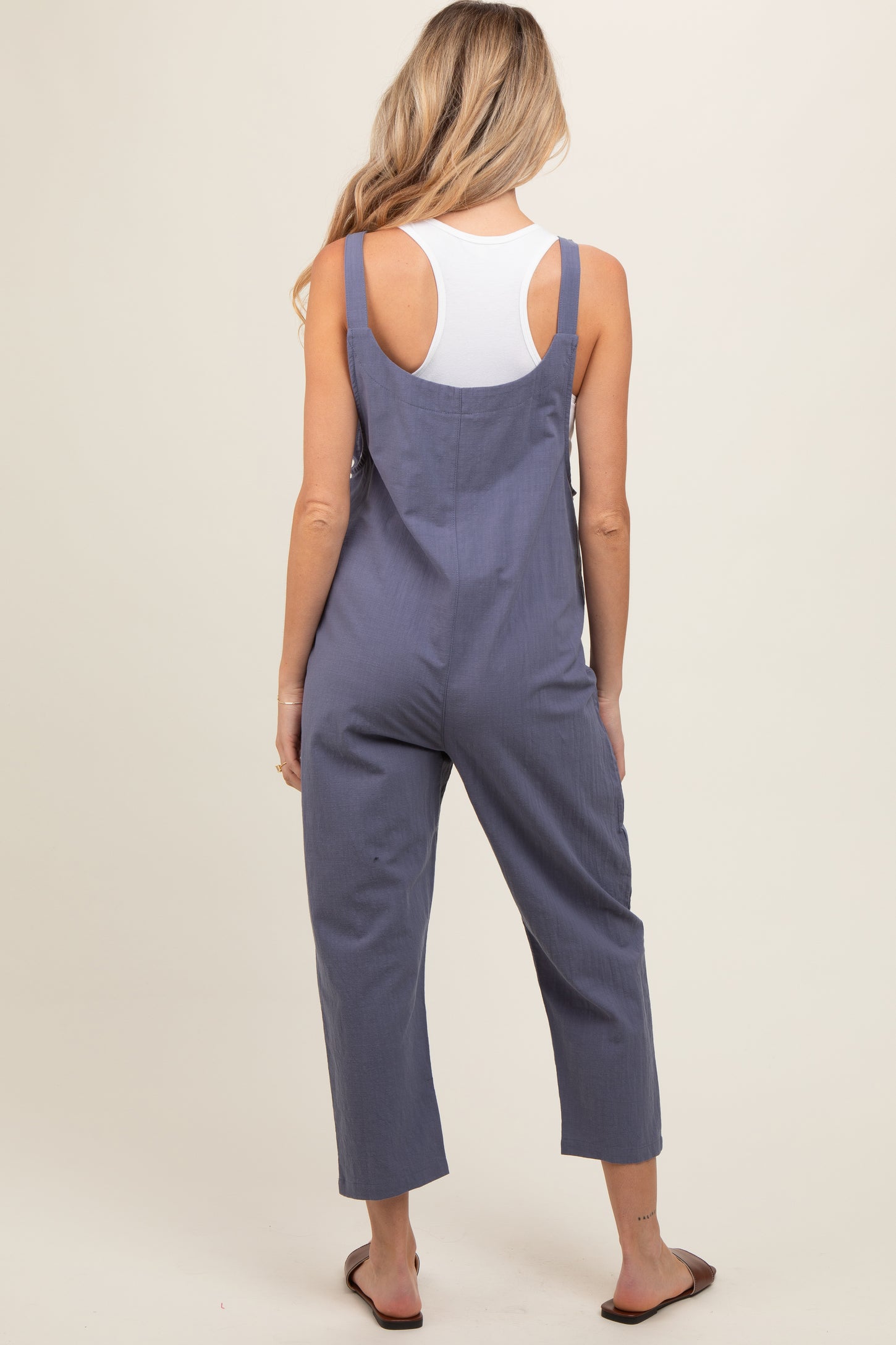 woman wearing a navy blue maternity jumpsuit with cropped legs and adjustable straps, seen from the back