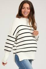woman wearing a cream and black striped maternity sweater with a relaxed fit and visible baby bump