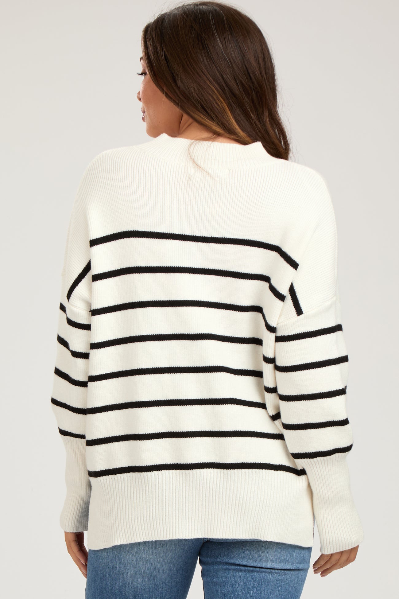 woman wearing a cream and black striped maternity sweater, showing the back style with loose-fitting sleeves