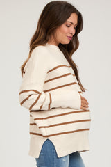 woman wearing a cream and brown striped maternity sweater, gently cradling her baby bump