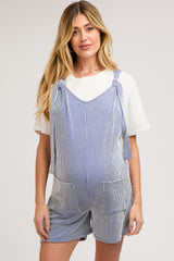 woman wearing a blue and white striped maternity romper with tie straps and pockets, showing her baby bump