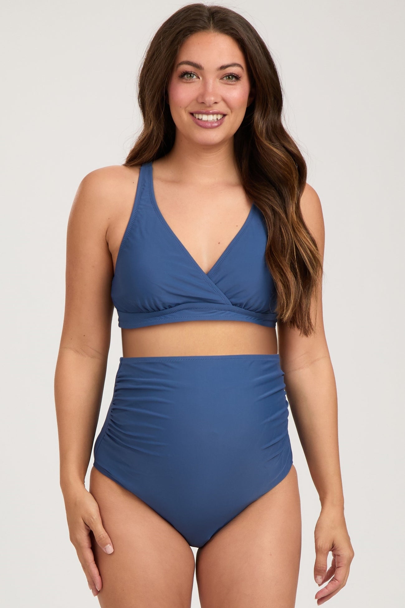 woman wearing a blue maternity bikini top and high-waisted bikini bottoms, showing a baby bump