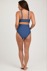 woman wearing a dark blue high-waisted maternity bikini showing her pregnant belly from the back