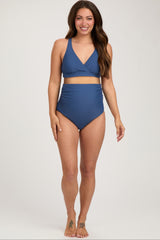 woman wearing a blue maternity bikini with a wrap-style top and high-waisted bottoms, showcasing her baby bump