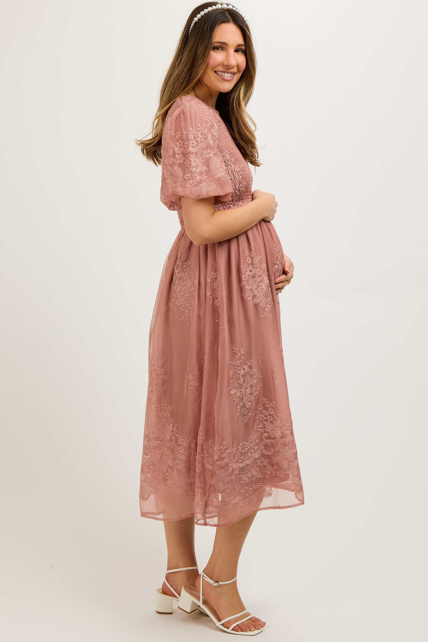 woman wearing a dusty rose maternity dress with floral embroidery and short sleeves, holding her baby bump