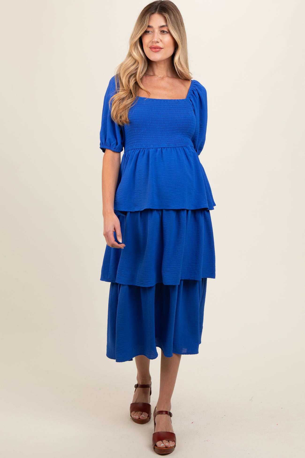 woman wearing a bright blue maternity dress with a square neckline and tiered skirt