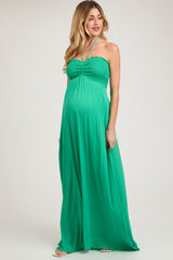 woman wearing a green strapless maternity maxi dress with a smocked bodice and a visible baby bump